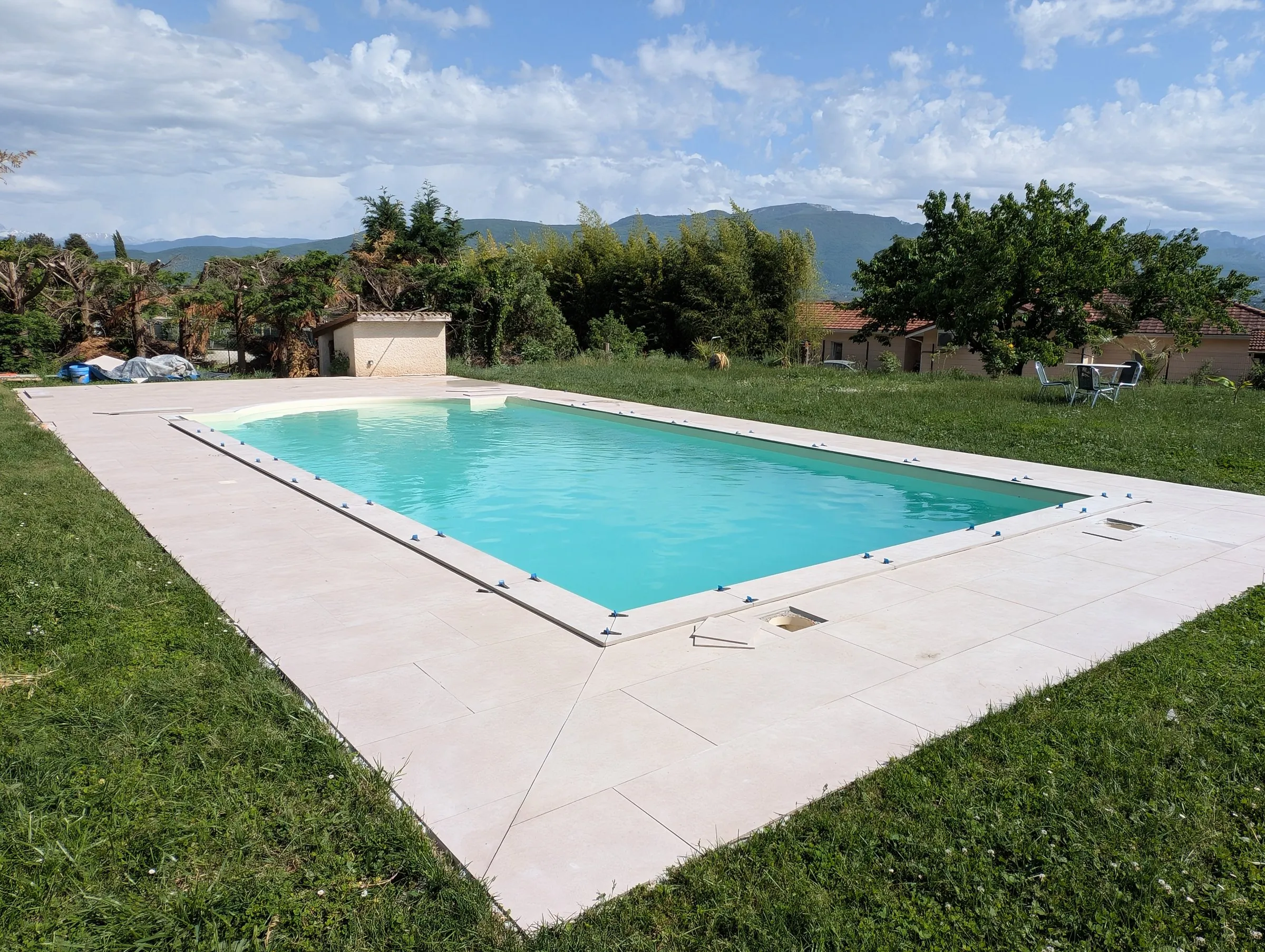 Piscine avec plage claire et pelouse face aux montagnes